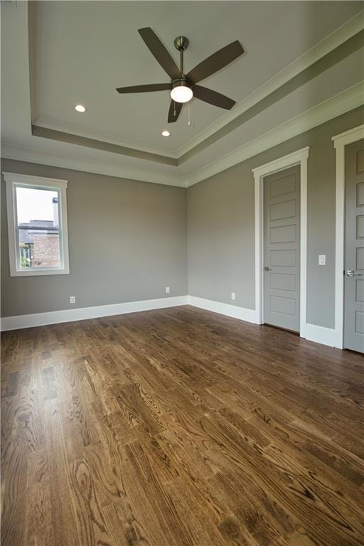 empty room with ceiling fan, wood-type flooring, ornamental molding, and a tray ceiling