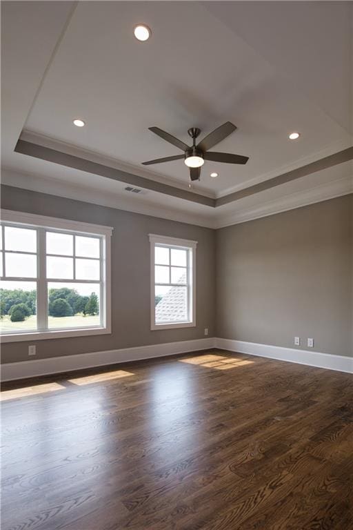 empty room with a tray ceiling, ceiling fan, hardwood / wood-style floors, and ornamental molding