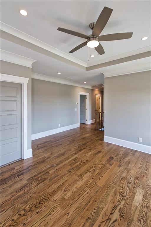 spare room featuring ceiling fan, crown molding, dark wood-type flooring, and a tray ceiling