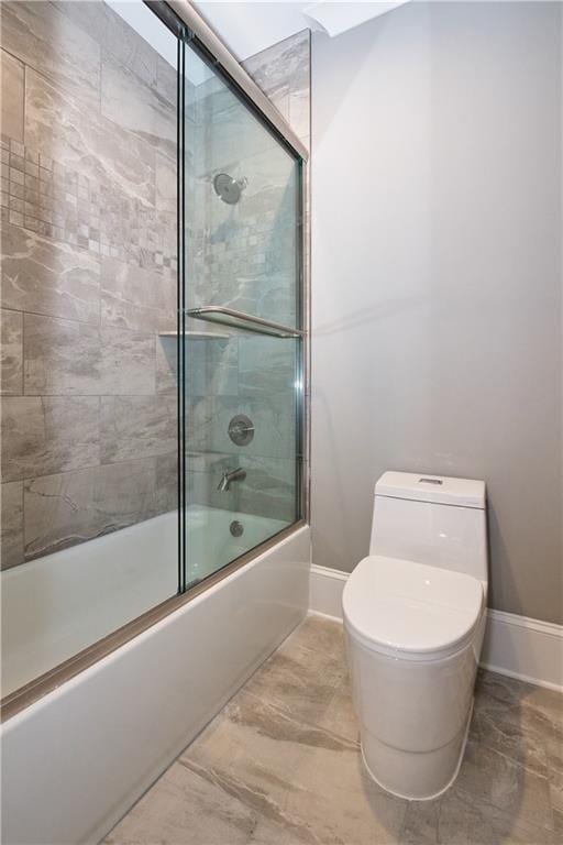 bathroom with tile patterned floors, toilet, and bath / shower combo with glass door