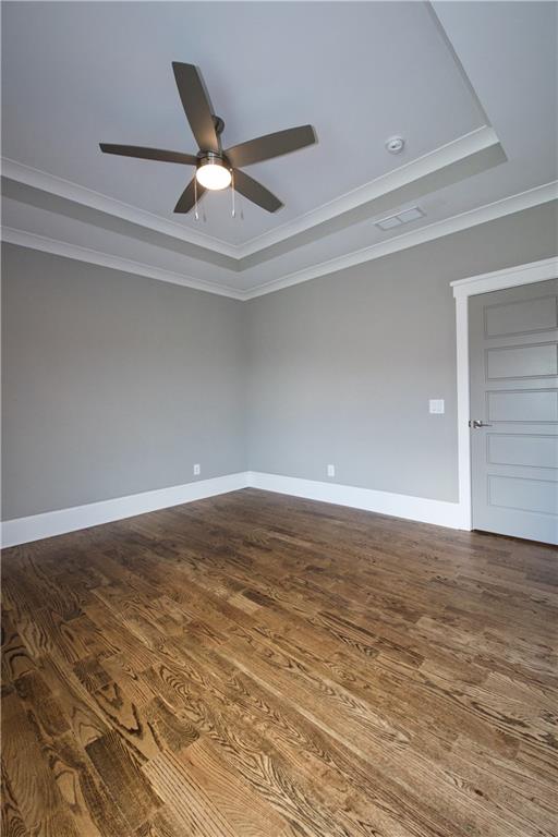 unfurnished room featuring ceiling fan, a raised ceiling, crown molding, and hardwood / wood-style flooring