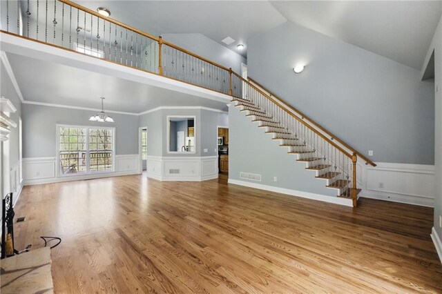 336 Toto Dr, Dawsonville, GA 30534 - unfurnished living room with stairway, a notable chandelier, high vaulted ceiling, visible vents, and wood finished floors