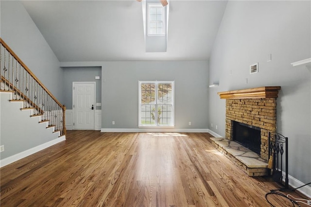 336 Toto Dr, Dawsonville, GA 30534 - unfurnished living room featuring a fireplace with raised hearth, high vaulted ceiling, stairs, baseboards, and wood finished floors