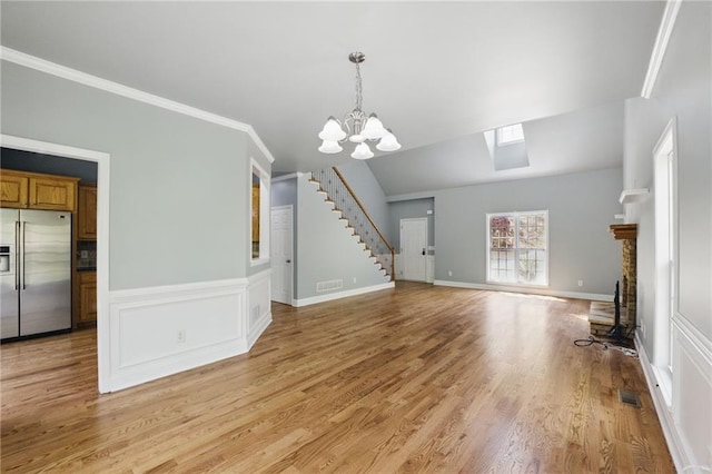 336 Toto Dr, Dawsonville, GA 30534 - unfurnished living room with a chandelier, light wood-type flooring, stairs, visible vents, and ornamental molding