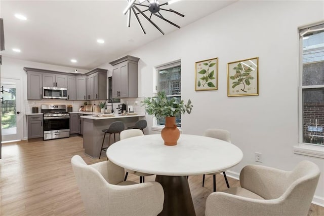 dining area with sink, a notable chandelier, and light hardwood / wood-style flooring