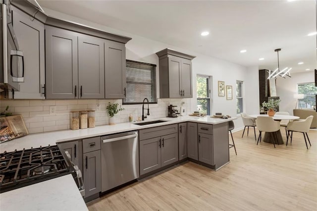 kitchen with appliances with stainless steel finishes, sink, a breakfast bar area, hanging light fixtures, and kitchen peninsula