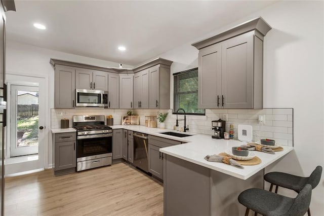 kitchen with gray cabinets, appliances with stainless steel finishes, sink, and kitchen peninsula