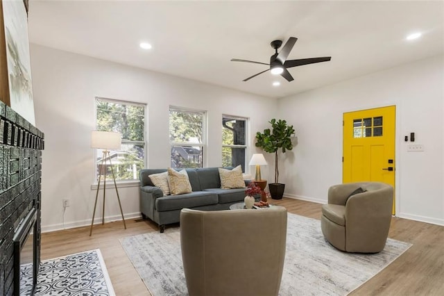 living room with ceiling fan, hardwood / wood-style floors, and a tile fireplace