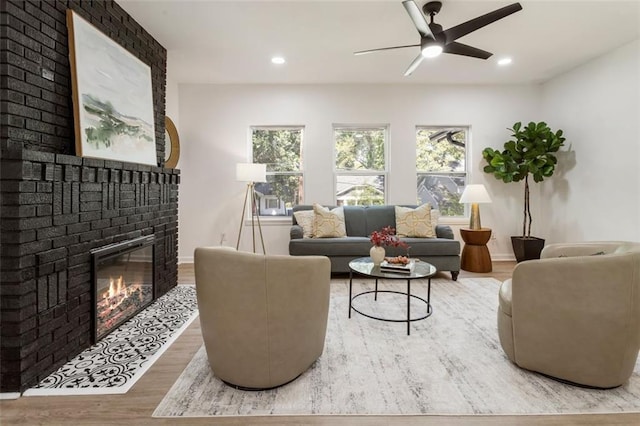 living room featuring hardwood / wood-style flooring, a brick fireplace, and ceiling fan