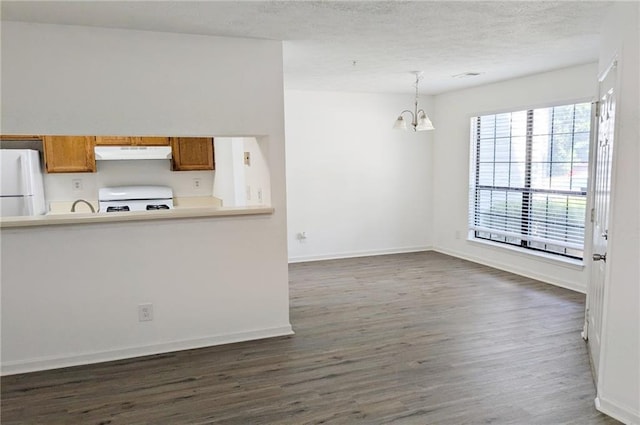 kitchen featuring dark hardwood / wood-style flooring, a notable chandelier, stove, white fridge, and decorative light fixtures