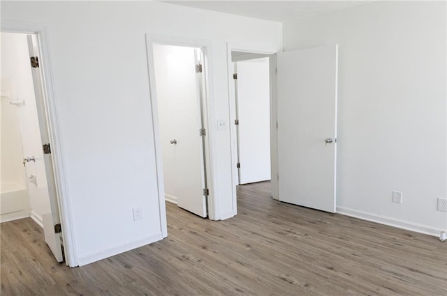 unfurnished bedroom featuring ensuite bath and light wood-type flooring