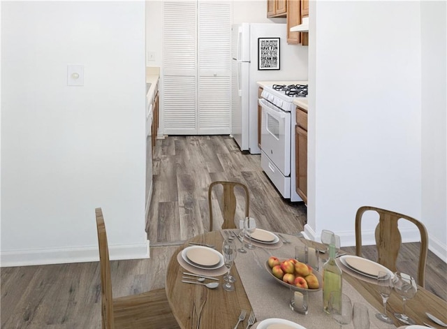 kitchen featuring white appliances, light hardwood / wood-style floors, and range hood