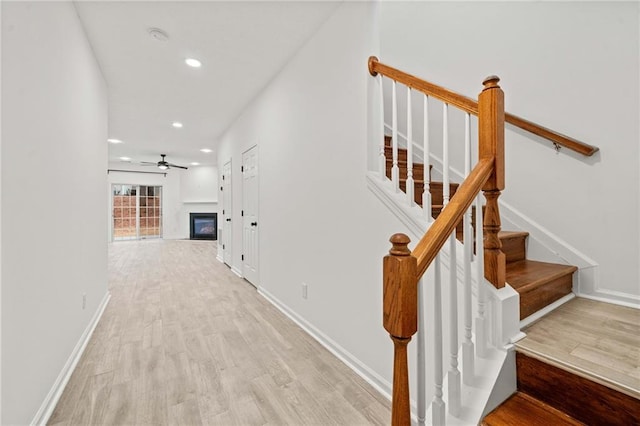 stairs featuring hardwood / wood-style flooring and ceiling fan