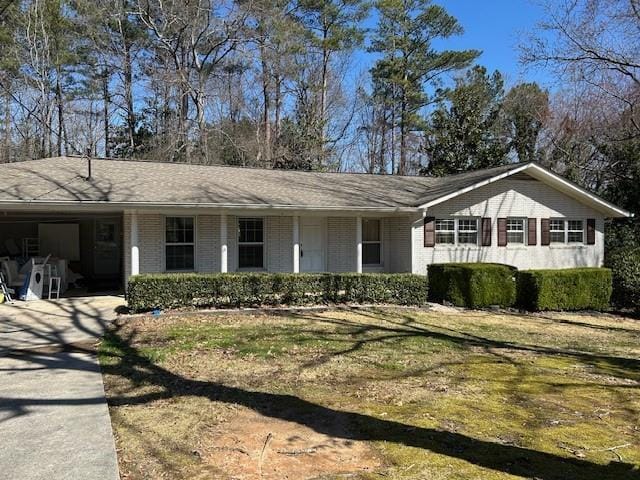 ranch-style home featuring brick siding, an attached carport, concrete driveway, and a front yard