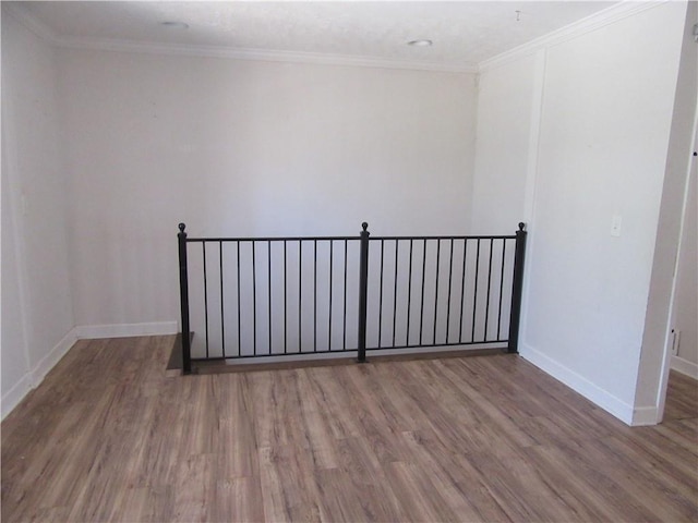 unfurnished room with crown molding, wood finished floors, and baseboards