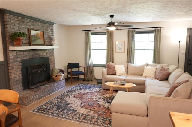 living room featuring a fireplace, a textured ceiling, ceiling fan, and a healthy amount of sunlight