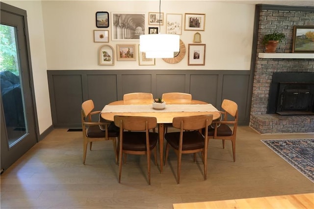 dining space featuring light hardwood / wood-style flooring and a brick fireplace