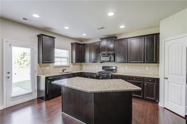 kitchen with dark hardwood / wood-style floors, a center island, black appliances, dark brown cabinetry, and sink