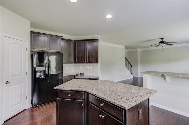 kitchen with ornamental molding, black fridge, dark brown cabinets, and a center island