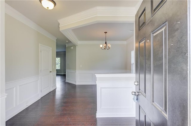 foyer with an inviting chandelier, ornamental molding, and dark hardwood / wood-style flooring