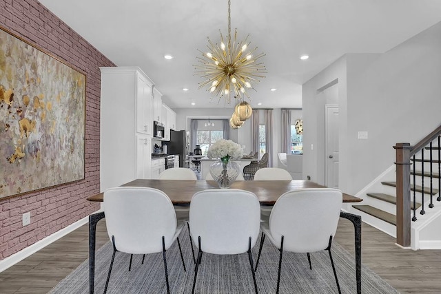 dining space with an inviting chandelier, brick wall, stairway, and dark wood finished floors