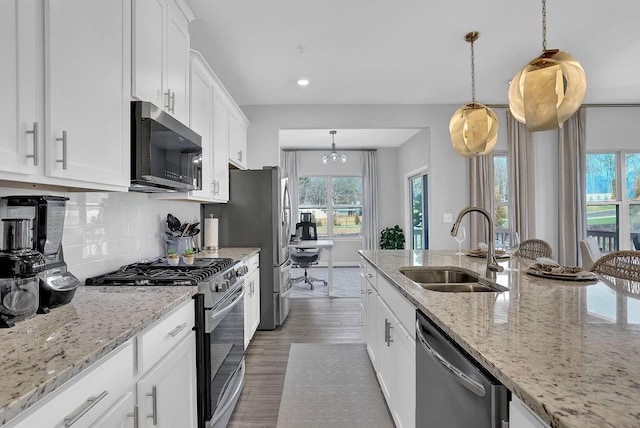 kitchen with tasteful backsplash, white cabinets, appliances with stainless steel finishes, wood finished floors, and a sink