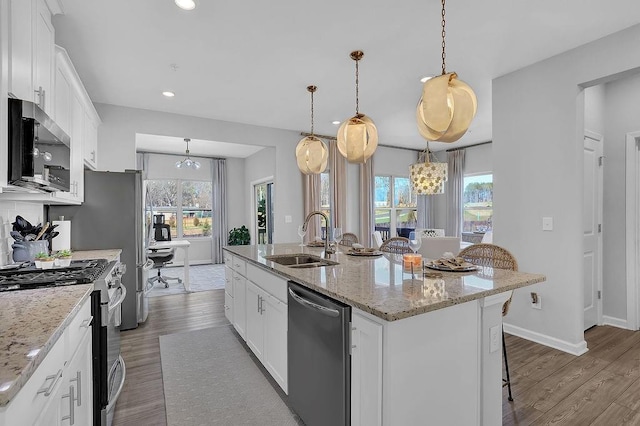 kitchen featuring stainless steel appliances, wood finished floors, a sink, and white cabinetry