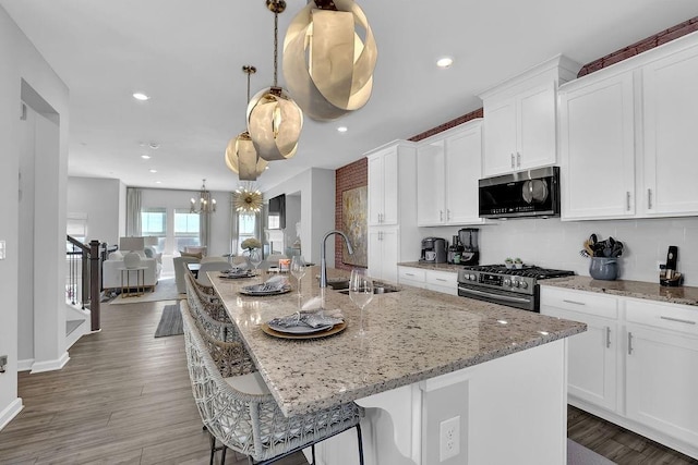 kitchen with a chandelier, a sink, white cabinetry, appliances with stainless steel finishes, and a large island with sink