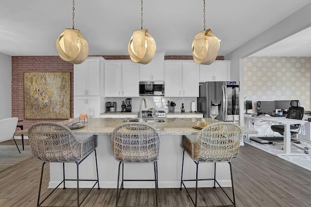 kitchen featuring stainless steel appliances, a large island, wood finished floors, and white cabinetry