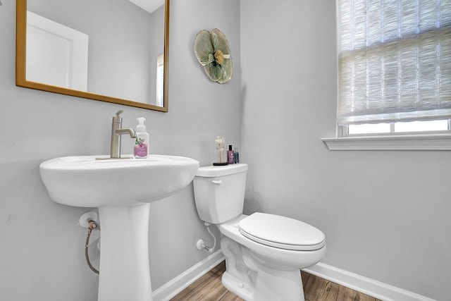 half bathroom with toilet, baseboards, and wood finished floors