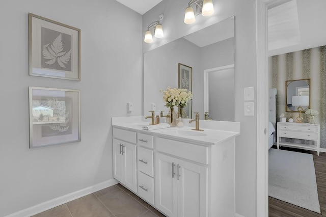 full bath featuring tile patterned flooring, connected bathroom, a sink, baseboards, and double vanity