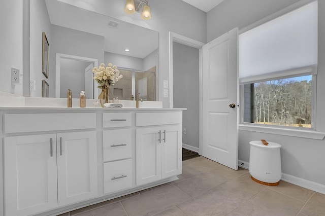 full bathroom featuring double vanity, a sink, a shower stall, baseboards, and tile patterned floors