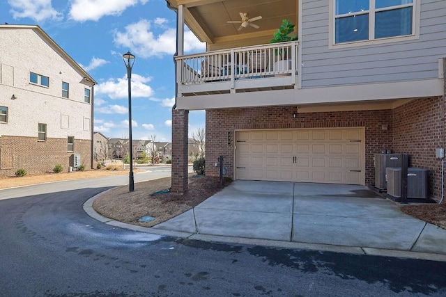 view of property exterior featuring brick siding, central air condition unit, concrete driveway, ceiling fan, and a balcony