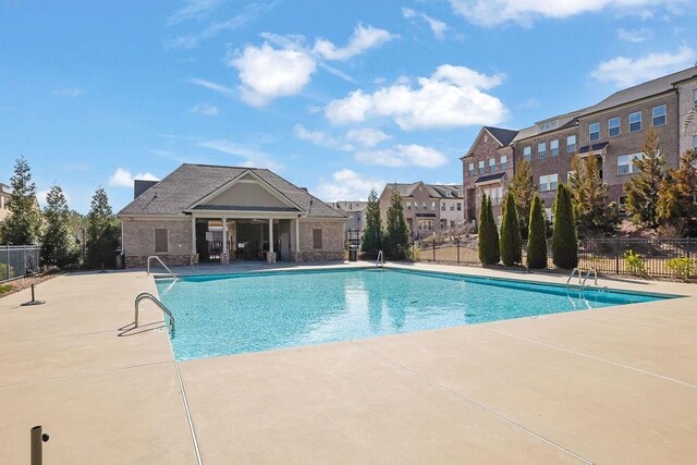 community pool with a patio area and fence