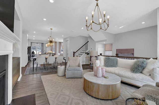 living area featuring stairs, recessed lighting, wood finished floors, and an inviting chandelier