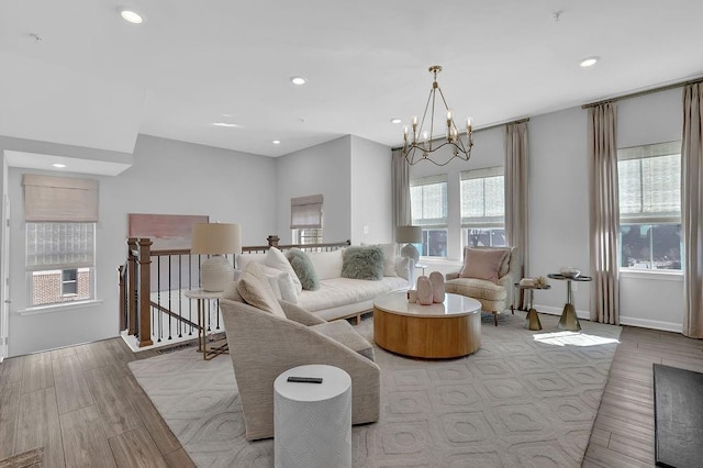 living room featuring baseboards, recessed lighting, wood finished floors, and an inviting chandelier