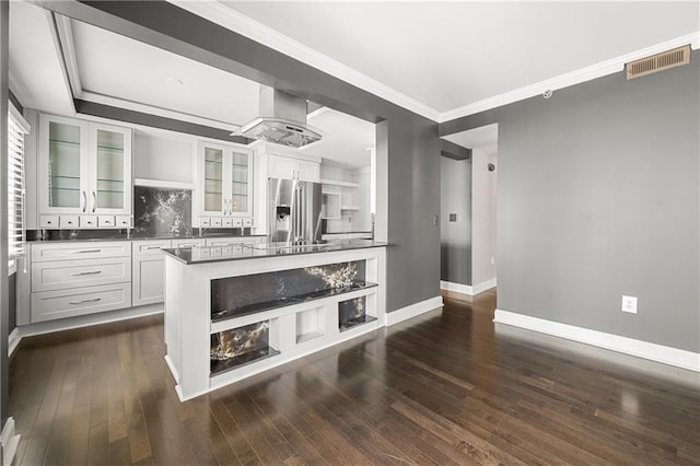 kitchen with dark wood-type flooring, crown molding, white cabinetry, stainless steel fridge with ice dispenser, and island exhaust hood