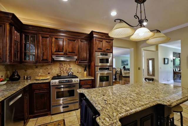 kitchen featuring a breakfast bar area, light tile floors, stainless steel appliances, a center island, and backsplash