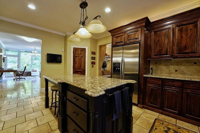 kitchen with decorative light fixtures, stainless steel fridge, a notable chandelier, a kitchen island, and tasteful backsplash