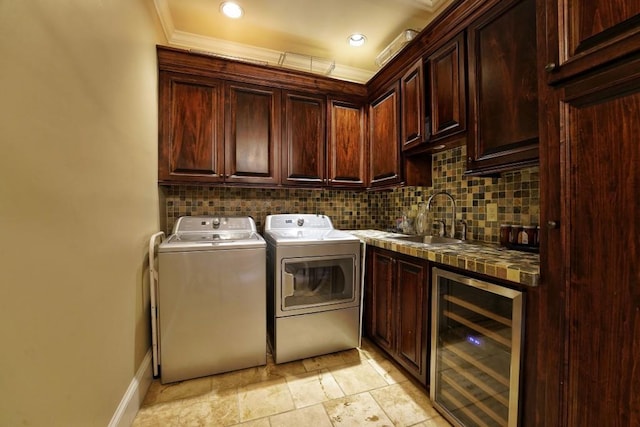 clothes washing area with light tile flooring, cabinets, sink, beverage cooler, and independent washer and dryer