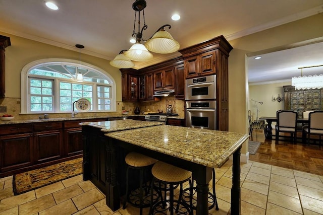 kitchen featuring a chandelier, a center island, tasteful backsplash, and light stone countertops