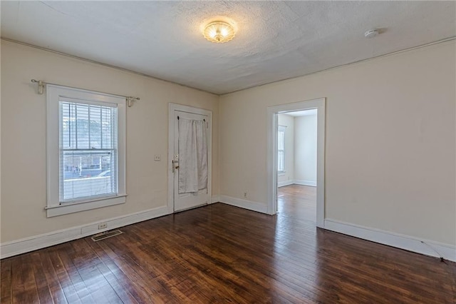 empty room featuring dark wood-type flooring and a textured ceiling