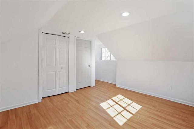 additional living space with light hardwood / wood-style floors and lofted ceiling