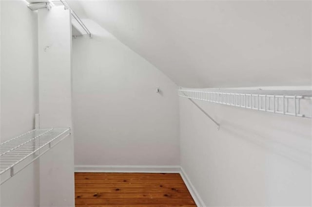 spacious closet with hardwood / wood-style flooring and vaulted ceiling