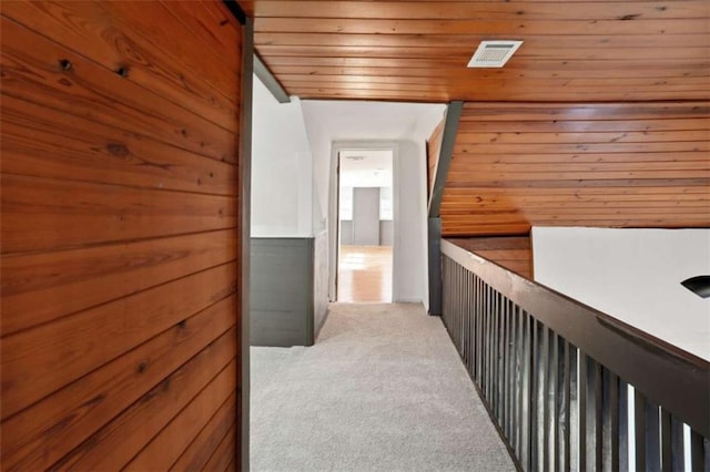 hall with wooden walls, wood ceiling, lofted ceiling, and light carpet