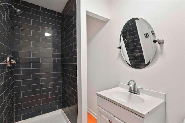 bathroom featuring tiled shower and vanity