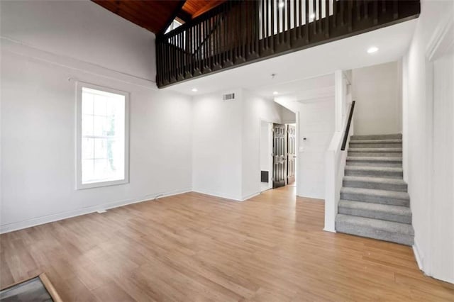 unfurnished living room featuring a high ceiling and light hardwood / wood-style flooring