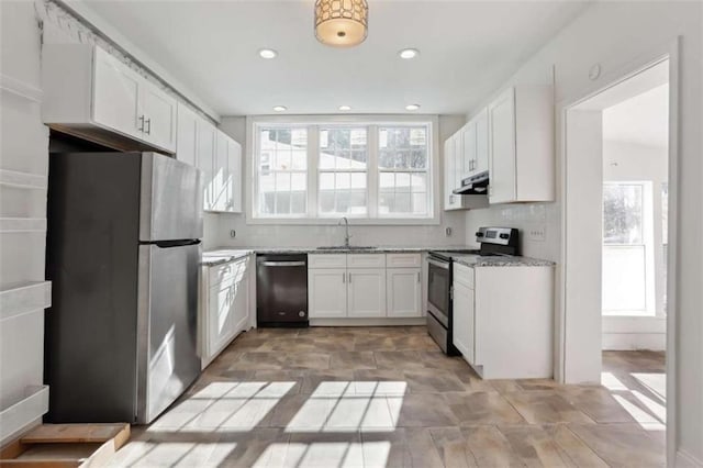 kitchen with decorative backsplash, light stone counters, stainless steel appliances, sink, and white cabinets