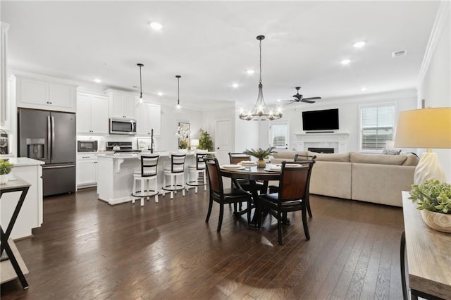 dining area featuring recessed lighting, dark wood-type flooring, a fireplace, visible vents, and crown molding