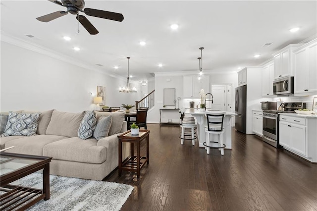 living area featuring ornamental molding, recessed lighting, dark wood finished floors, and stairs